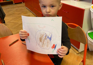 Chłopiec pokazuje swoją pracę