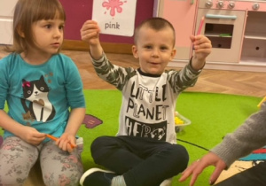 chłopiec prezentujący kartę obrazkową z kolorem "pink" oraz różową kredkę