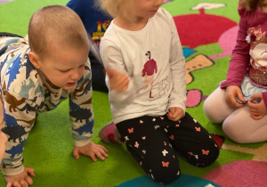 dzieci na dywanie przyglądające się kartom obrazkowym z kolorami