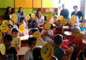 dzieci pokazują uśmiechnięte minki z papieru