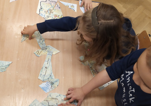 dzieci układają puzzle z mapą