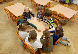 Dzieci grają przy stolkiu w memory/memo.