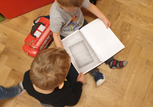 Chłopcy oglądają książeczkę z symbolami narodowymi