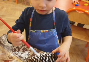 Chłopiec maluje szyszkę