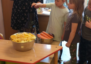 Dzieci pod opieką pani Magdy wrzucały owoce i warzywa do wyciskarki.