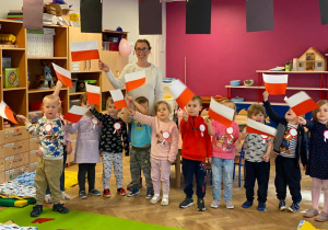 Dzieci i nauczycielka machają flagami