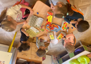 dzieci przy stolikach podczas pracy nad ozdabianiem pudełek