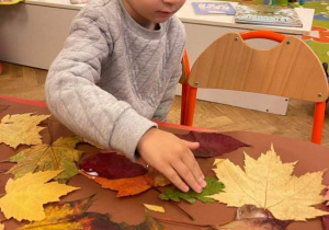 Chłopiec przykleja zielony liść.