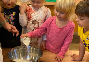 dziewczynka wsypuje mąkę do miski