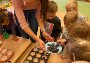 nauczycielka rozdaje dzieciom po kawałeczku gorzkiej czekolady