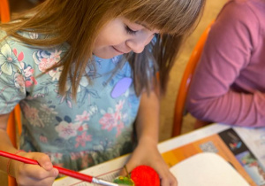 Dziewczynka maluje farbą połówkę jabłka