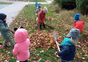 Dzieci zamiatają liście.