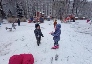 Dzieci w zaśnieżonym ogrodzie.