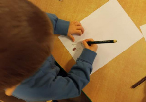Chłopiec rysuje choinkę.