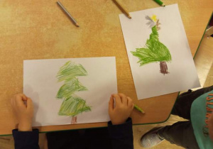 Dzieci prezentują narysowane przez siebie choinki.