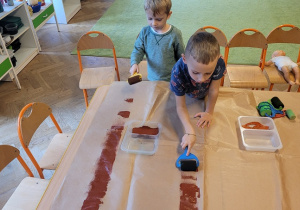 Dzieci malują brązową farbą