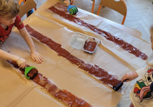 Dzieci malują brązową farbą