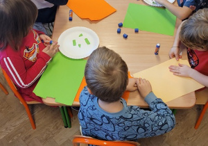 Dzieci wyklejają papierowe talerzyki kolorowymi skrawkami papieru