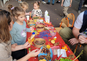 Dzieci przy stole robią ozdoby z darów jesieni