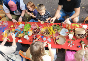 Dzieci przy stole robią ozdoby z darów jesieni