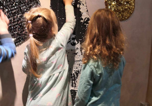 Dzieci dotykają wypukłych, o różnej chropowatości przedmiotów na ścianach w teatrze
