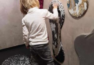 Dzieci dotykają wypukłych, o różnej chropowatości przedmiotów na ścianach w teatrze