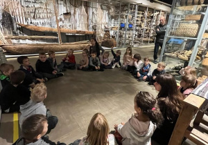 Dzieci siedzą na podłodze w Muzeum Etnograficznym i słuchają opowieści