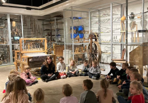 Dzieci siedzą na podłodze w Muzeum Etnograficznym i słuchają opowieści