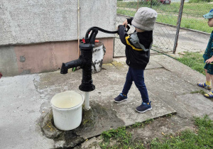 Dziecko pompuje wodę ze studni