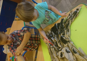Dzieci malują drzewo farbą