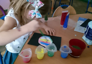 dziewczynka maluje farbami bombkę